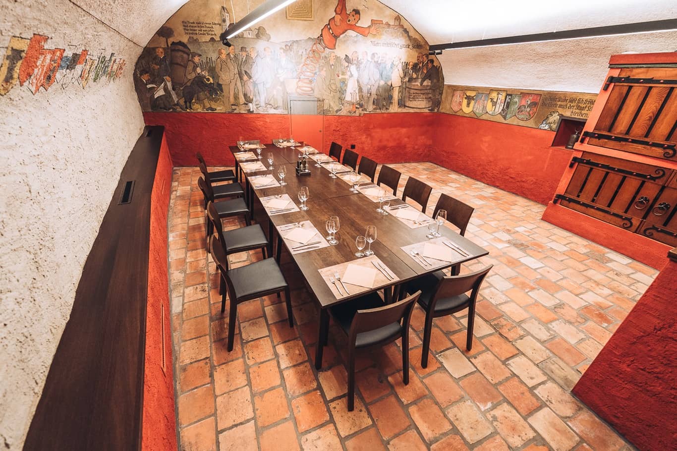 Der Staatskeller Schaffhausen mit seinen Fresken an der Wand ist mit einem Tisch und St&uuml;hlen ausgestattet, die f&uuml;r ein Bankett bereit stehen